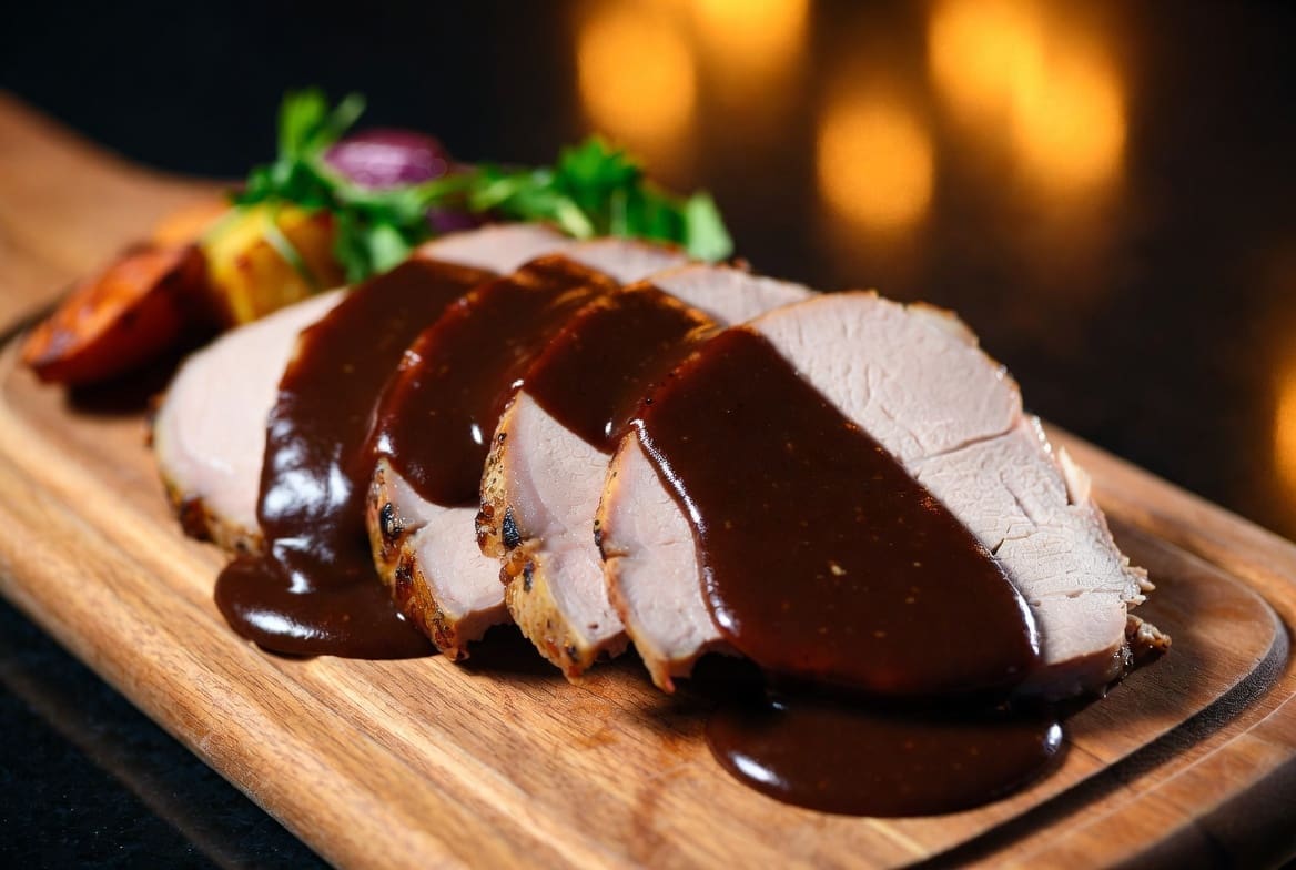 Sliced spit braai lamb South Africa served with rich gravy and roasted winter vegetables on a wooden board, cozy premium winter presentation, professional catering